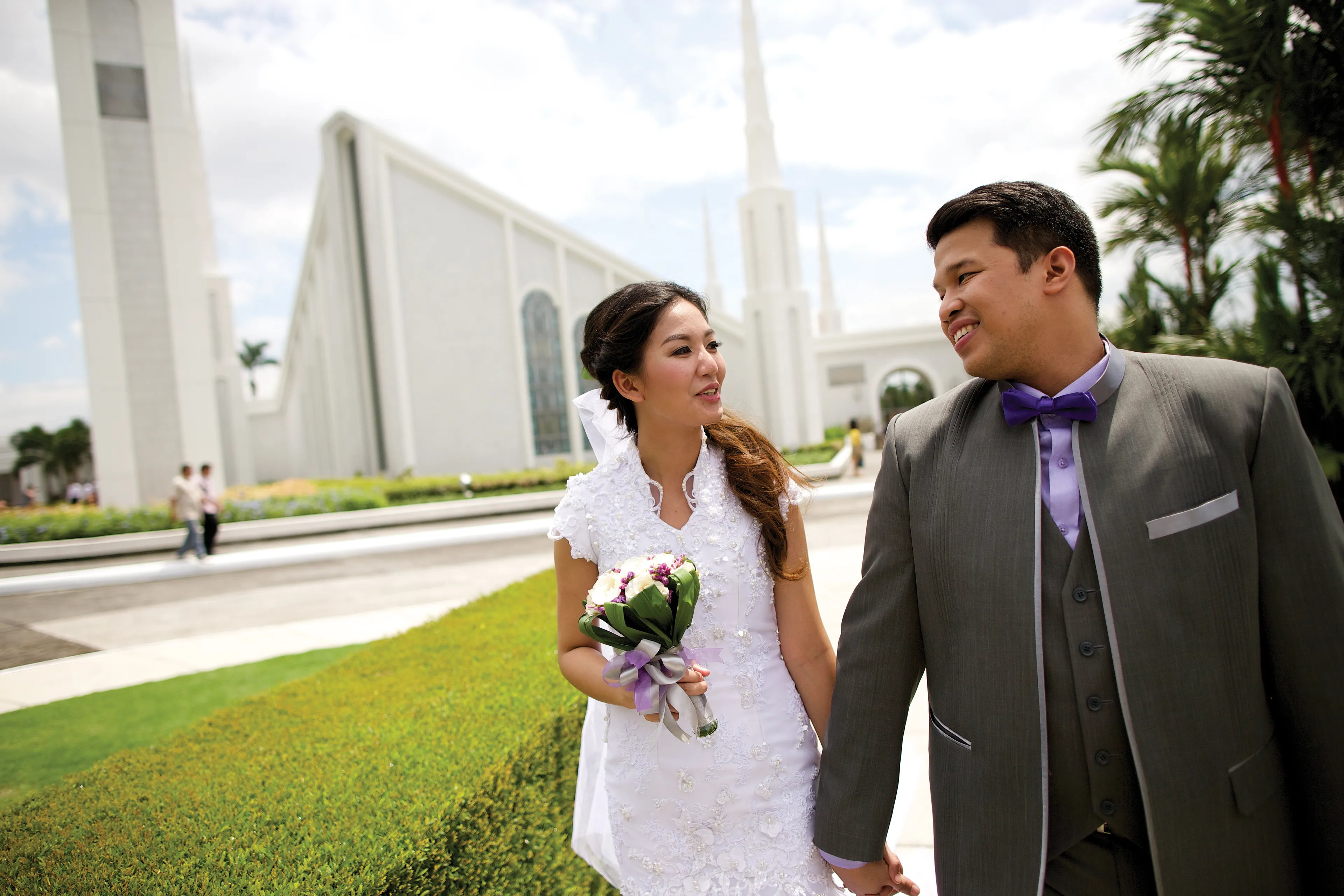A bride and groom walking outside the Manila Philippines Temple.