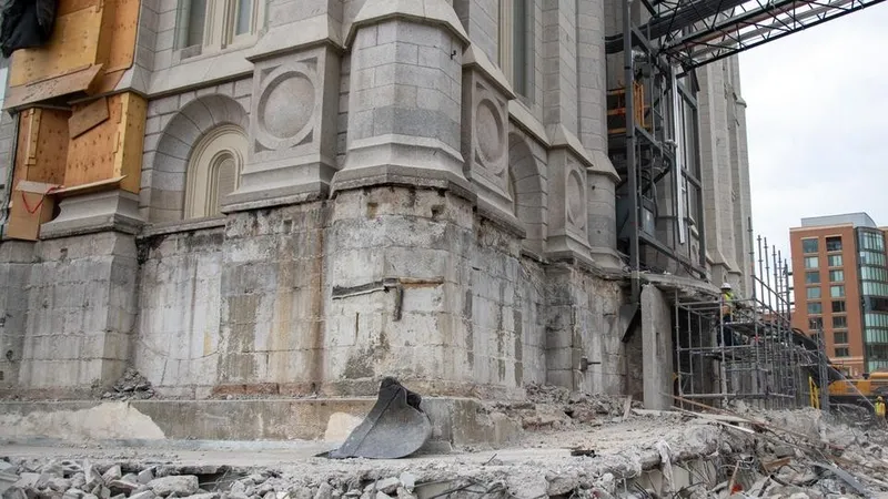 The Salt Lake Temple is under construction. Part of the temple has a tarp over the side, wooden support slats, and scaffolding. 