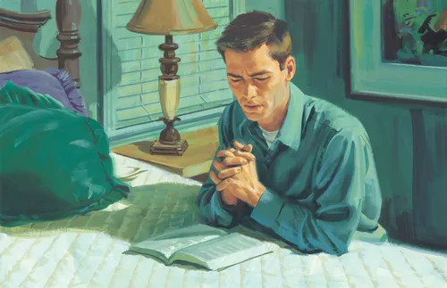 man kneeling and praying at his bedside