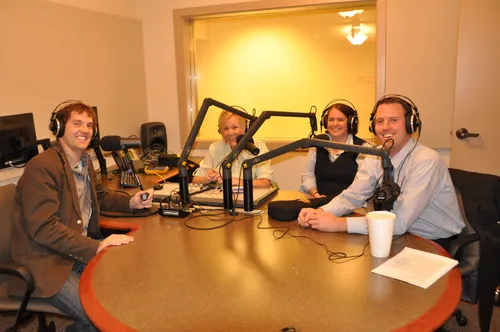 A group of people sitting at microphones around a table.