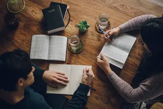 A couple study the Bible and the Book of Mormon at their kitchen table reading from Psalm 23:1, 4