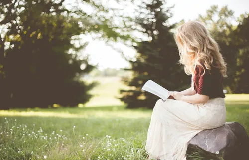 young woman sitting outside and reading
