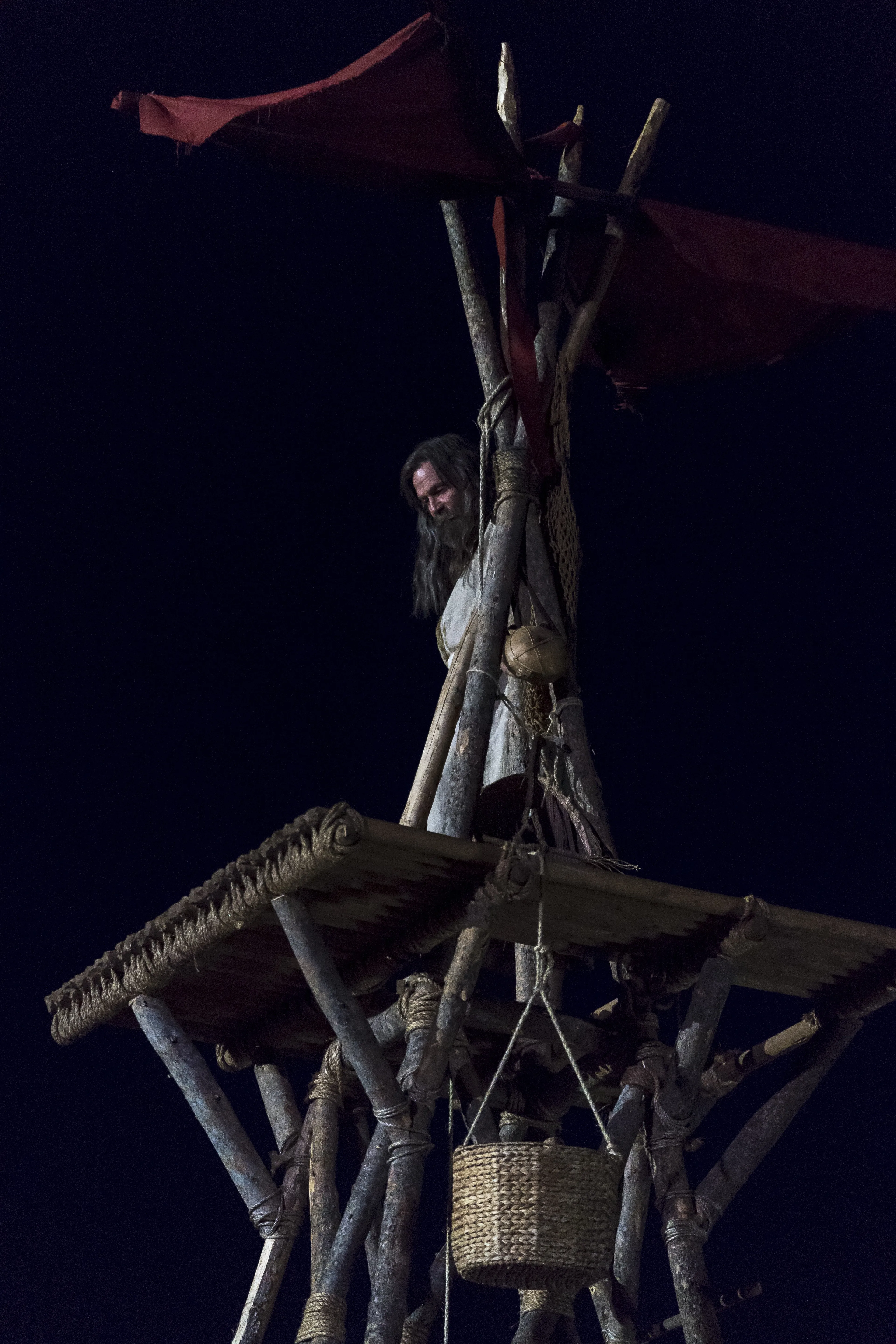 Older Jacob standing on the top of a tower at night.