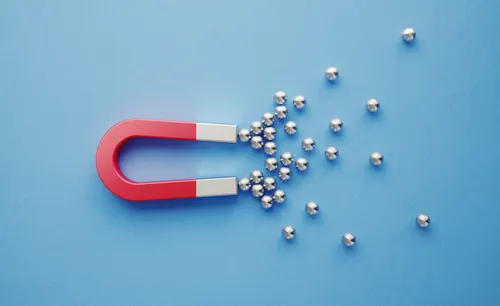 Silver Spheres Gravitated Towards a Red Magnet on Blue Background