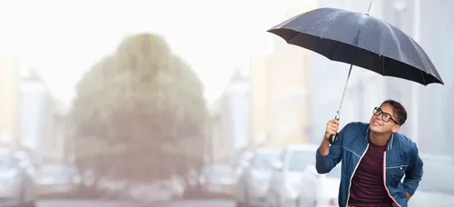 young adult smiling under umbrella