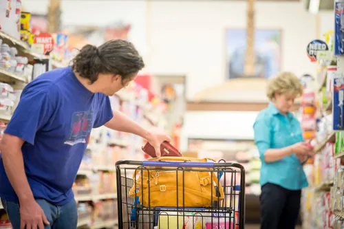 Stock images of a man stealing a purse from an oblivious female victim in a grocery store.