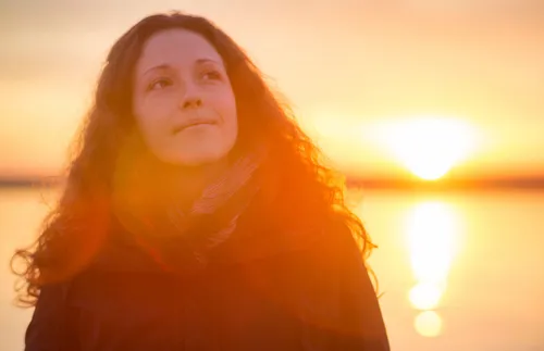 Young adult woman smiling up at the sky