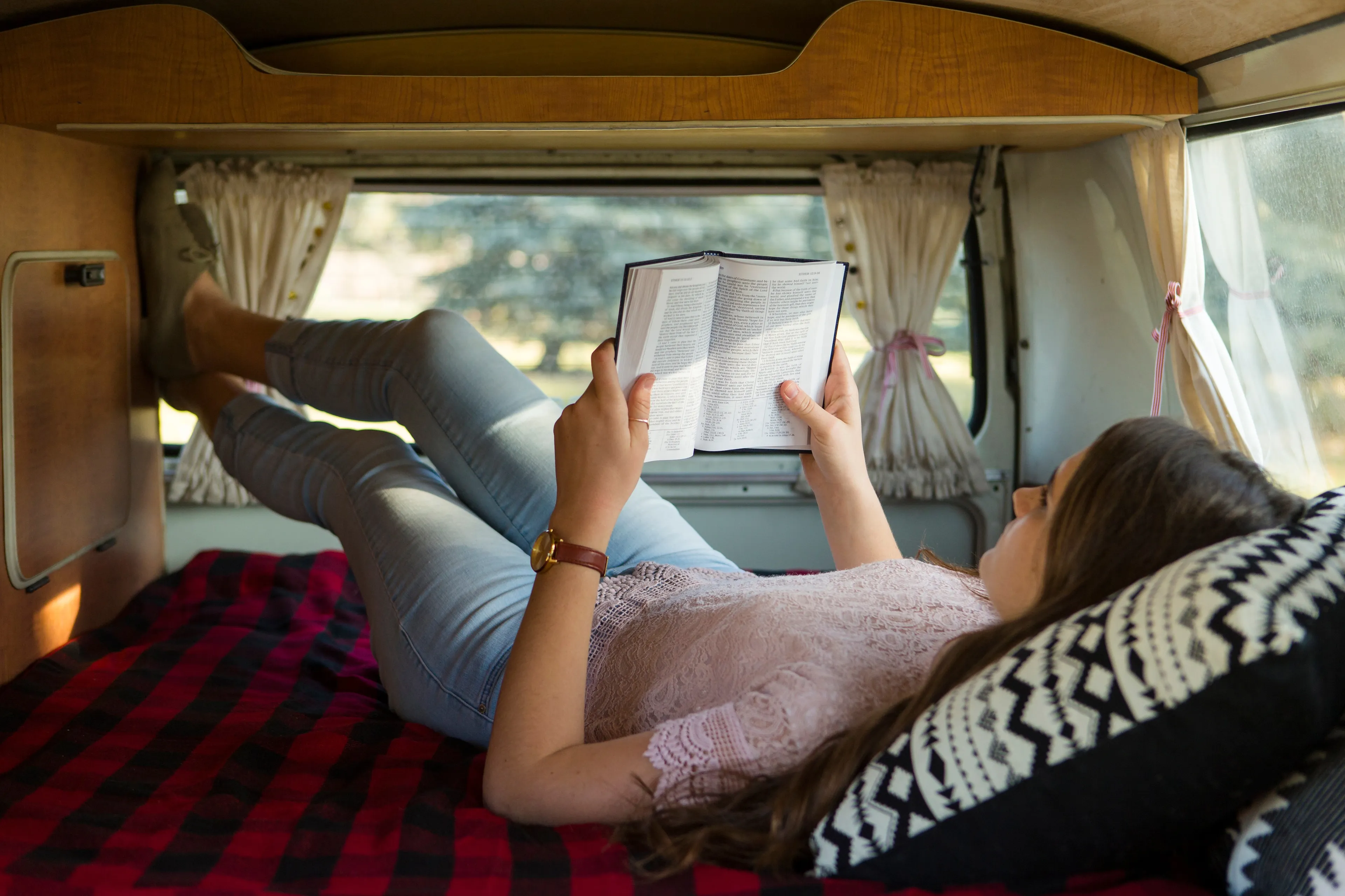 A young woman lying down and reading scriptures.