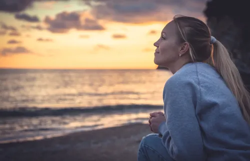 woman watching the sun set over the ocean