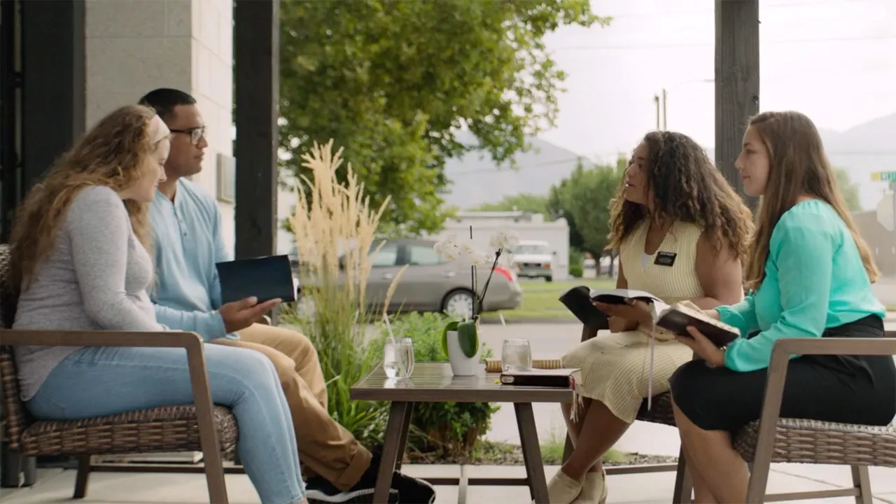 Missionaries teaching a young couple outside their home