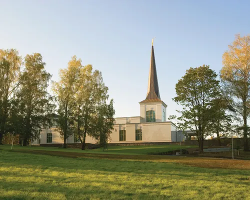 A side view of the Helsinki Finland Temple, seen at the top of a hill in the warm light of sunset.