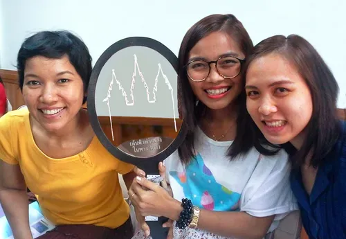 Thai young women with a mirror that says, “See Yourself in the Temple.”