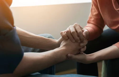 two young adults clasping hands