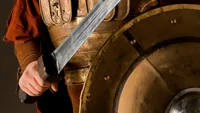 A young man dressed in New Testament era armor with a sword and shield.