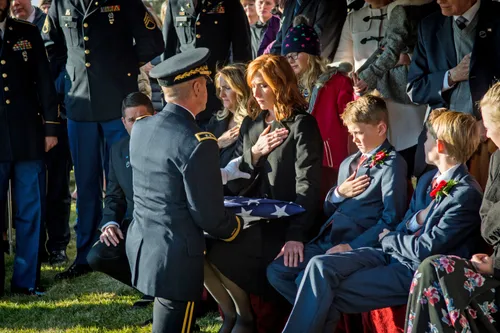 army serviceman presents flag to wife and children of Brent Taylor during his funeral services
