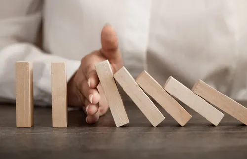 a hand stopping a row of blocks from falling