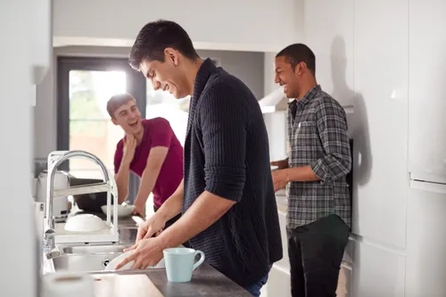 three young men in kitchen doing dishes together