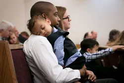 Tony and Marnie sit on a church pew learning about the gospel of Jesus Christ