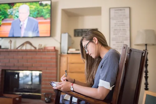 young woman taking notes during general conference