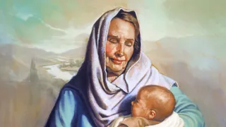 Sarah holds a baby Isaac in her arms. She looks down at him and smiles.