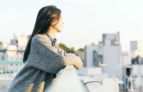 young adult looking over railing at the city