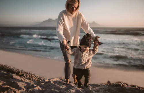 woman walking along the beach with a child