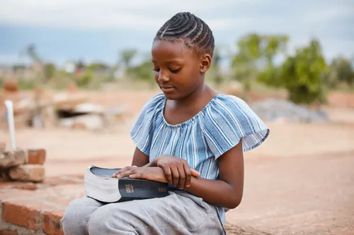 young girl praying outside with scriptures