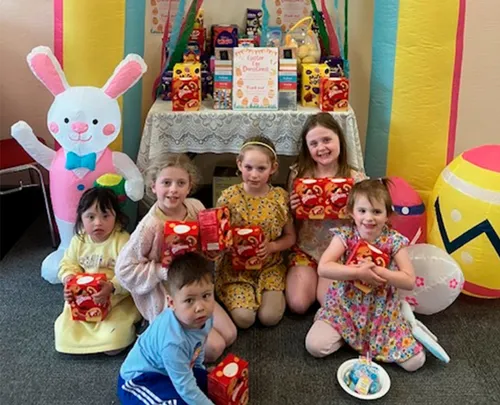 Photo of children holding gifts in front of an Easter display
