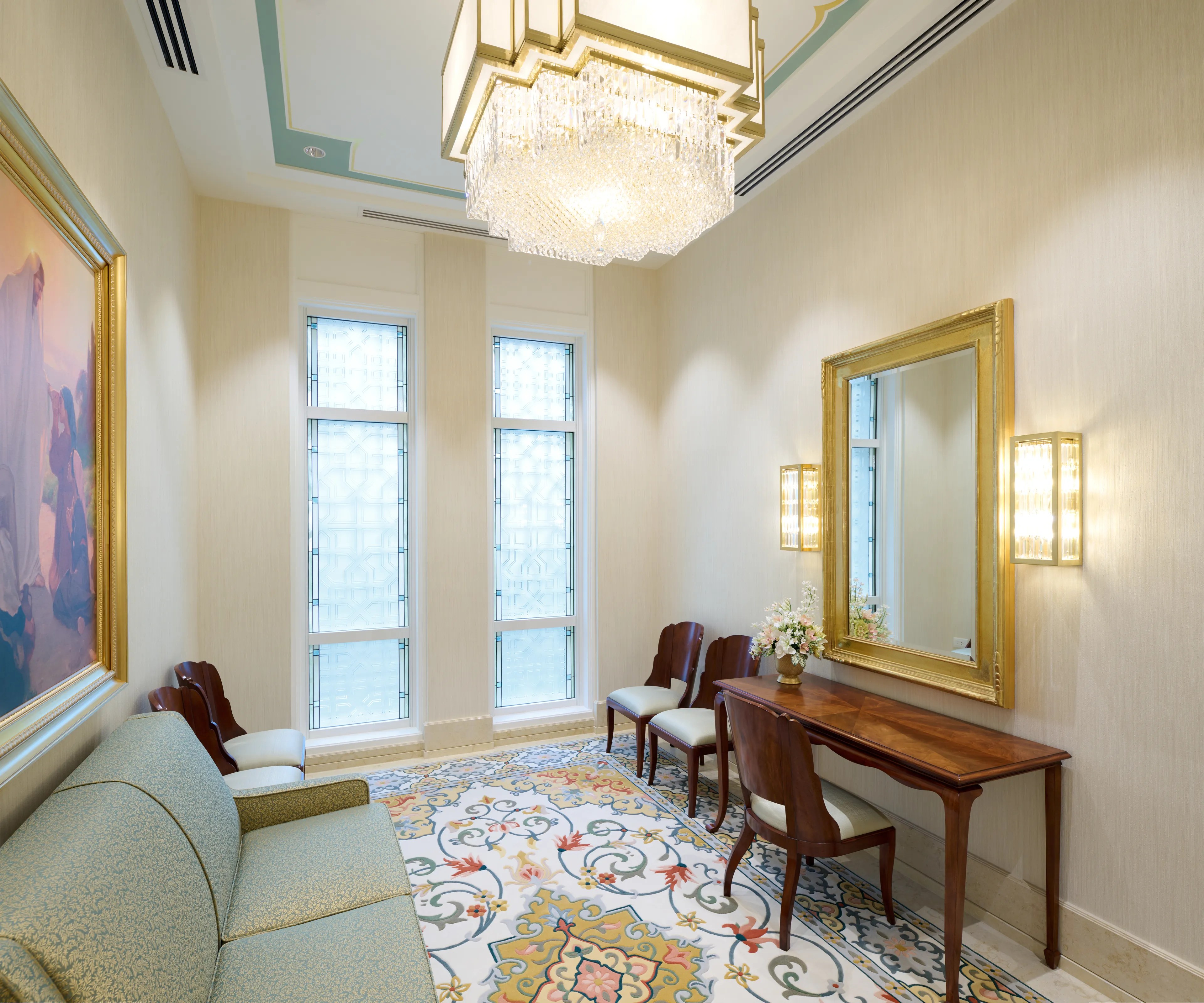 Interior image of the Bangkok Thailand Temple showing the bridal room. Image features chairs, artwork, stained glass windows, and a vanity mirror.