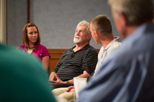 Men and women meeting together in an addiction recovery program.