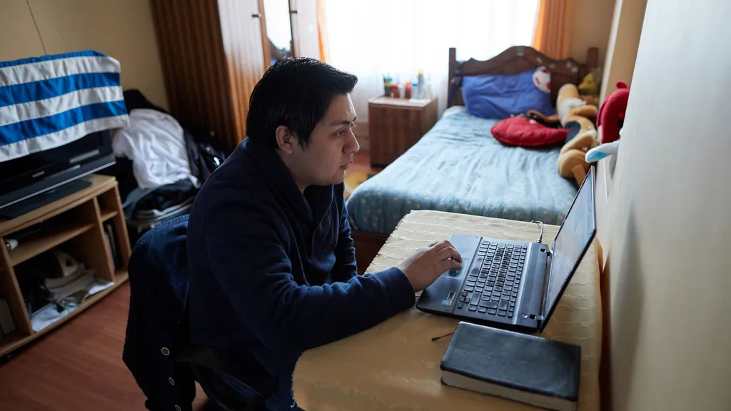 A young adult male looks at something on a computer.