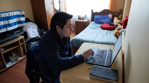 A young adult male looks at something on a computer.