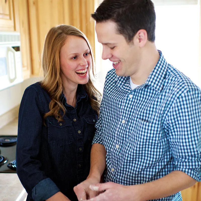 A couple stand in a kitchen enjoying each other’s company