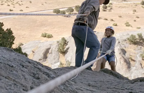 Young woman rappelling off a cliff
