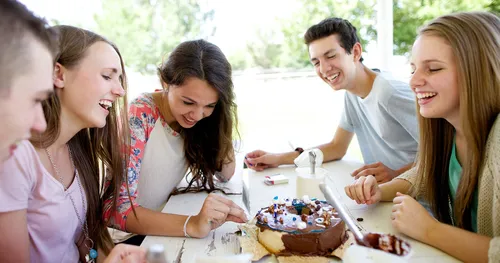 Young men and women decorating a cake