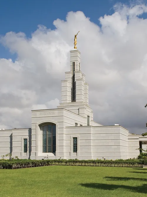 A green lawn, palm trees, and other vegetation surrounding the Accra Ghana Temple.