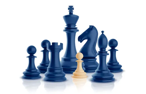 several blue chess piecess surrounding a tan chess piece