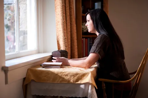 A woman looking out a window as she is pondering.