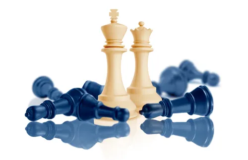 two tan chess pieces standing and several blue lying down