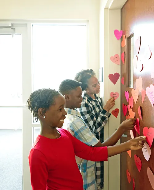 Children putting paper hearts on a door