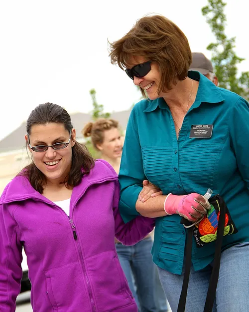 A Church-service missionary guides another as they walk together outside.