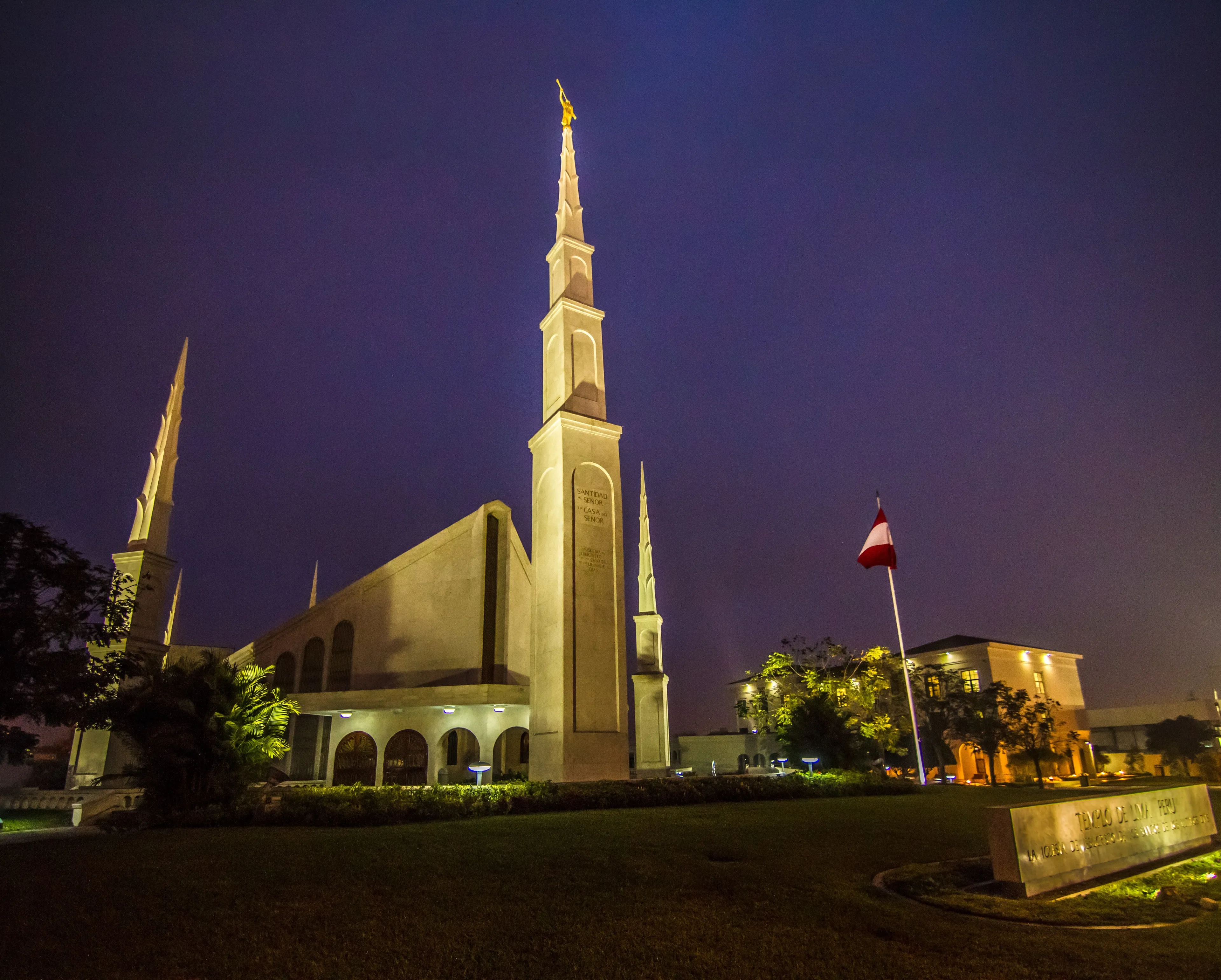 The Lima Peru Temple in the evening, with the entrance, spires, and name sign.