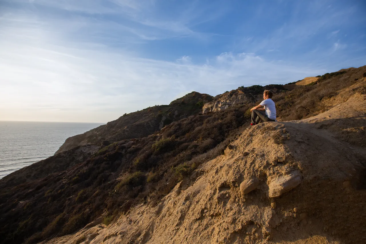 A woman siting above the sea on a cliff contemplates forgiveness and repentance