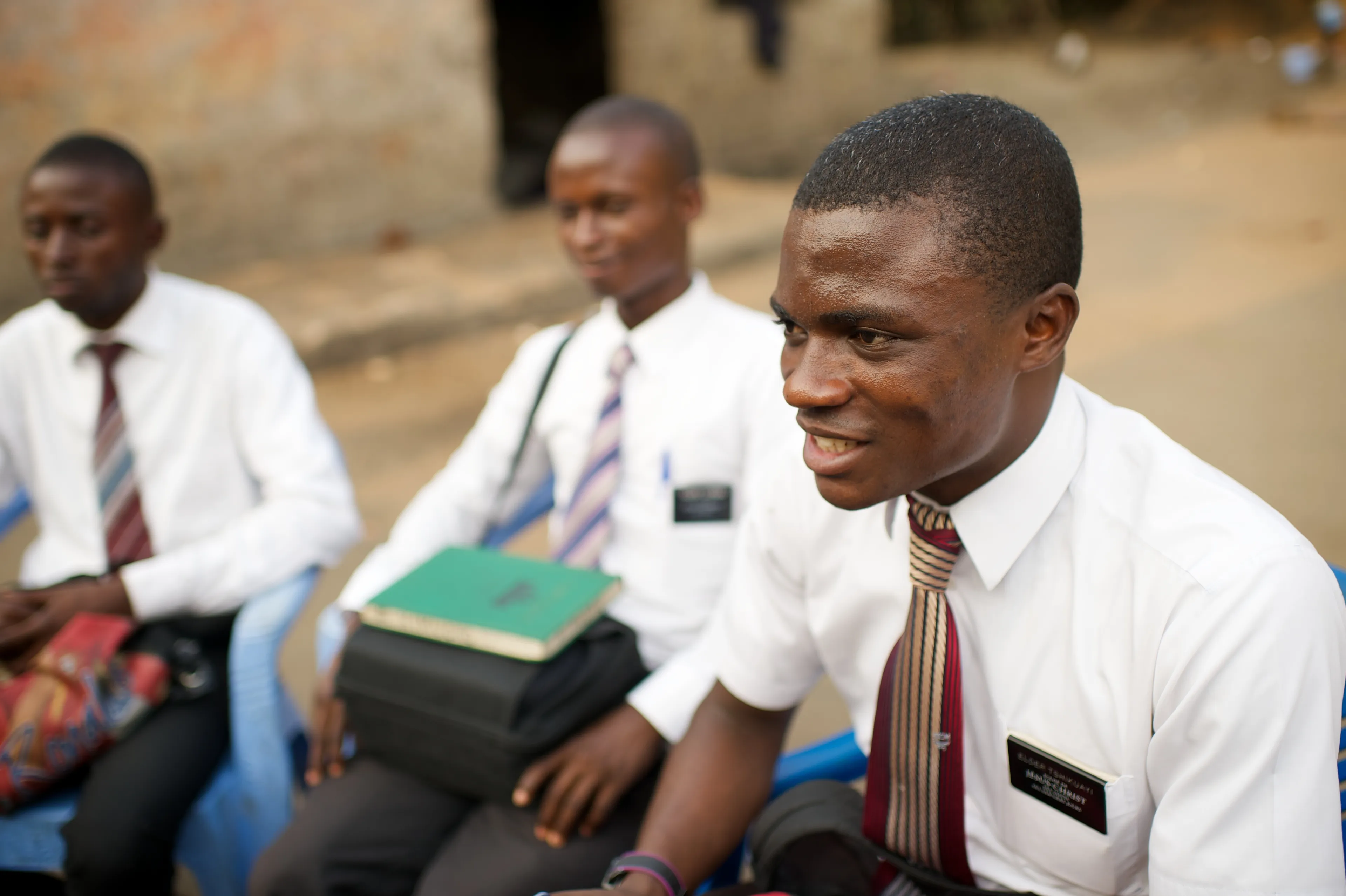 An elder sitting at a zone conference with two more elders sitting behind him.