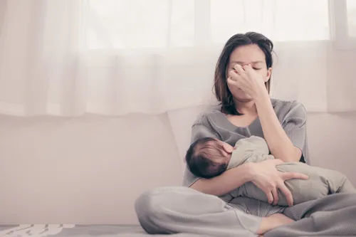 an exhausted mom holding an infant