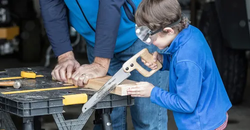 një djalosh dhe një burrë duke sharruar dru