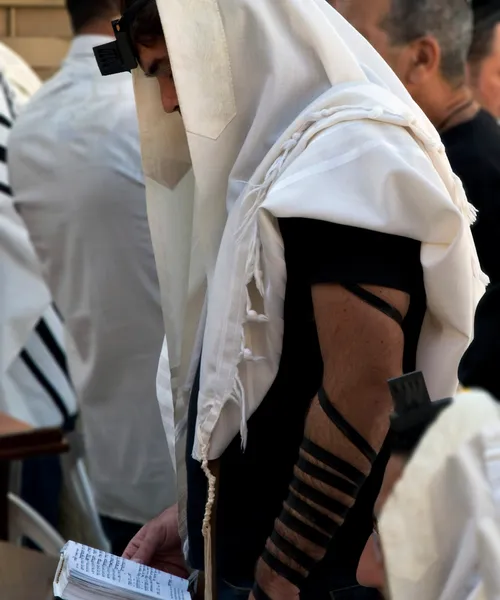 a man wearing modern phylacteries around his forearm and forehead