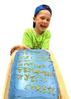 Smiling boy with a cake decorated to look like the Book of Mormon
