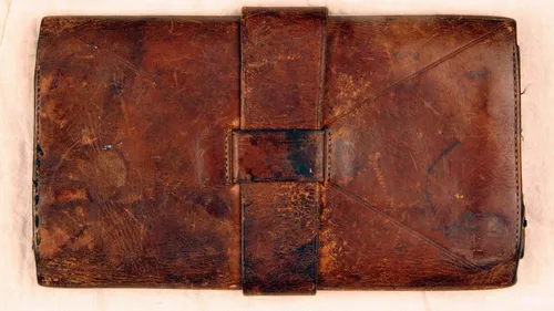 Larges leather wallet with strap closure.