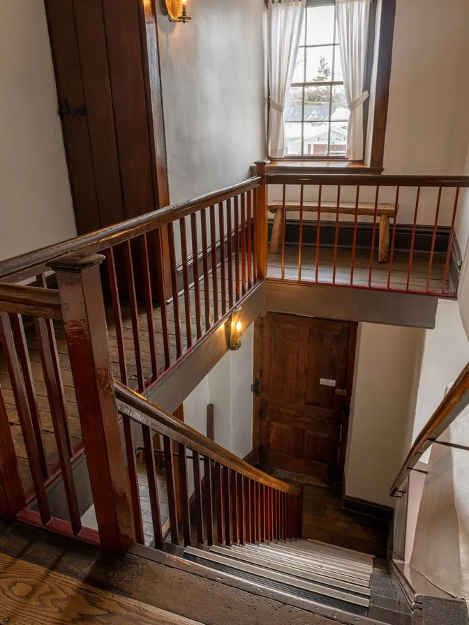 View from the top of the wooden stairs looking down at the front door of the building. 